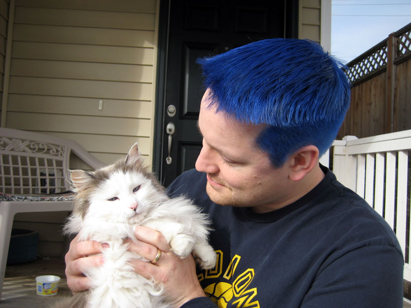 Adam with blue hair holding a cat